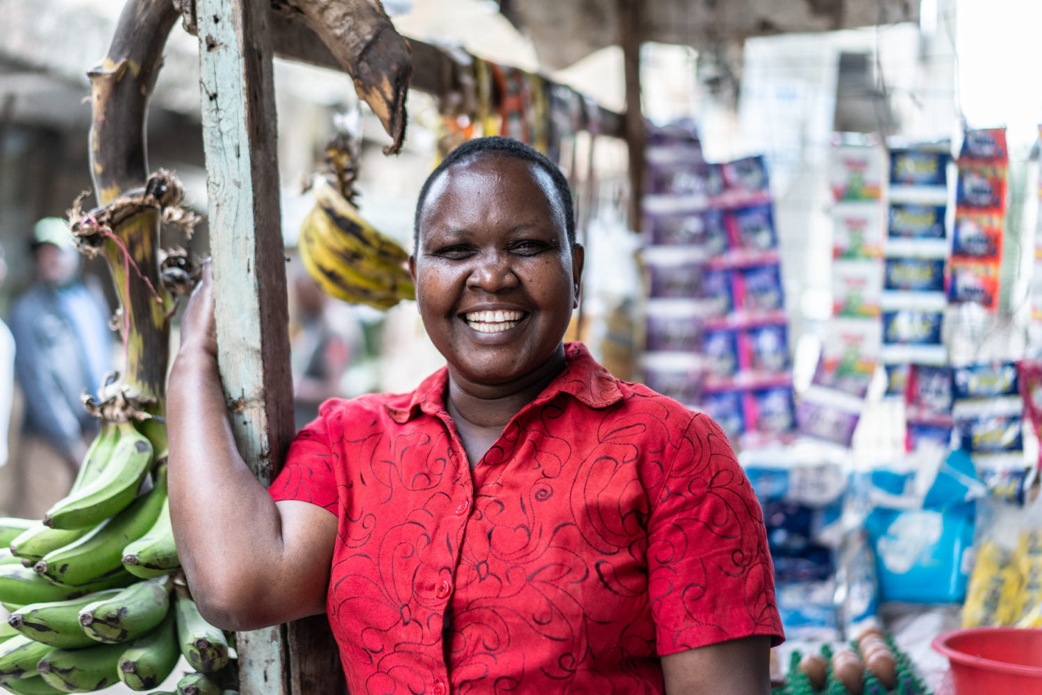 Juliet Kathendu is posing for a portrait next to her small shop where she sells vegetables, and household commodities along the street, Kayole, Kenya.