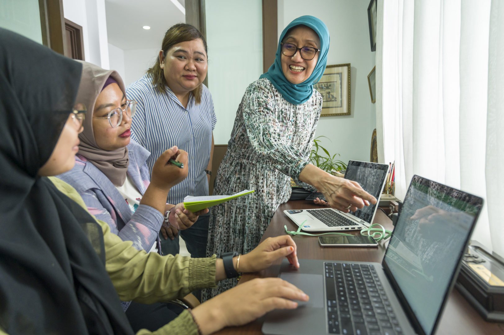 Jullie Hakim points to a screen while working with colleagues at her business