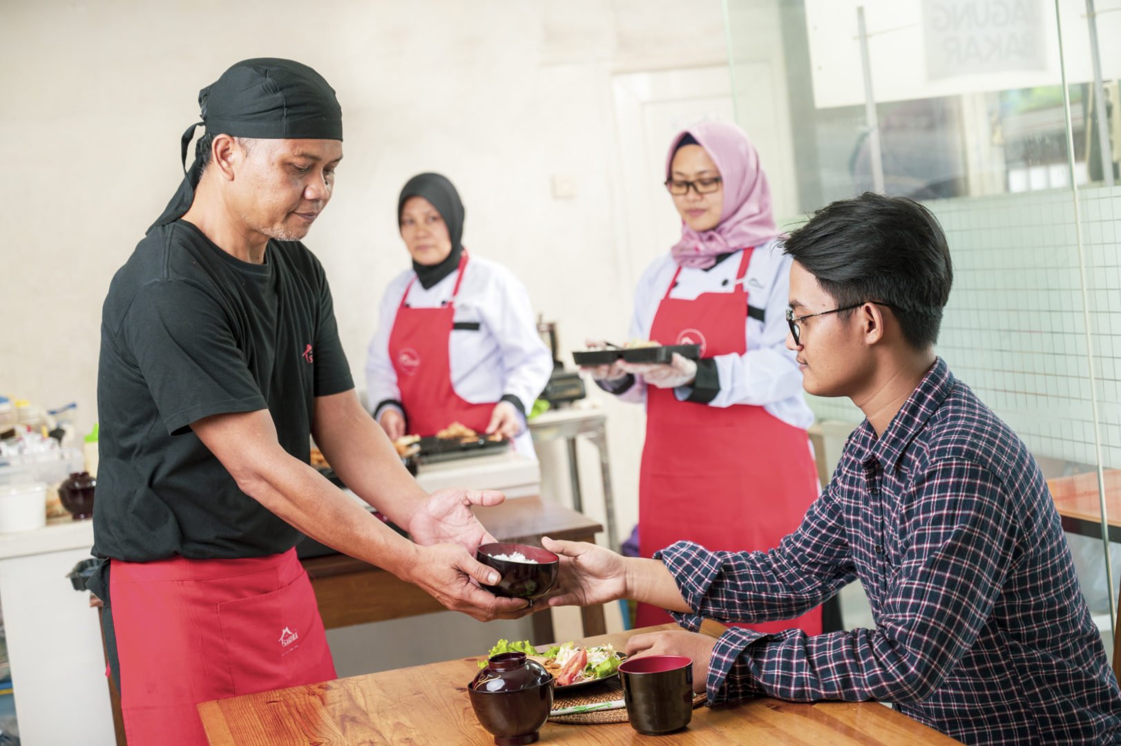 A patron is served food at Susi Lawati's Japanese restaurant Dapur Sakura