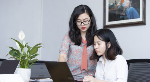 two women work at a computer together