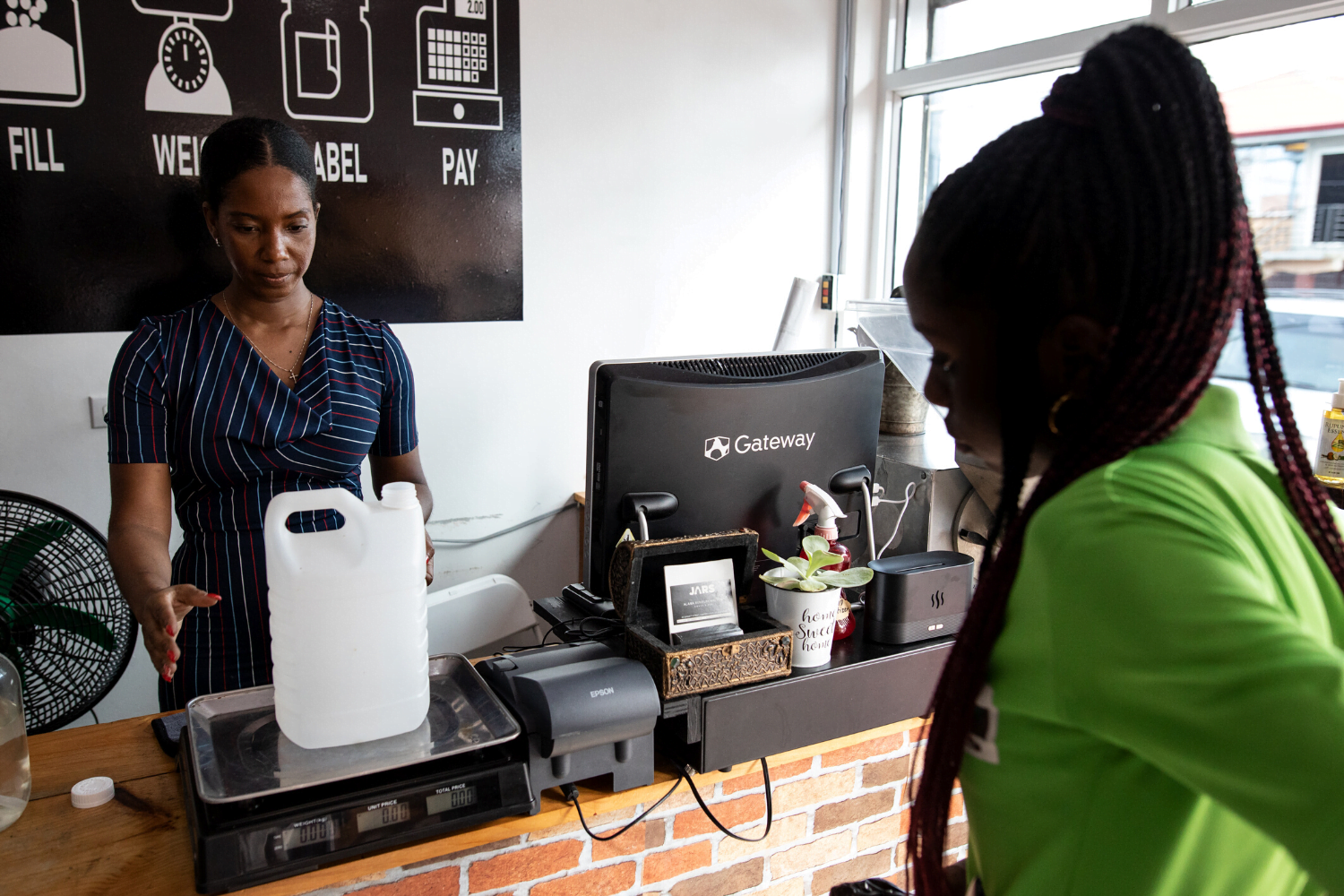 Alana Bunbury-Walton helps a customer weigh her products at JARS zero waste store in Guyana