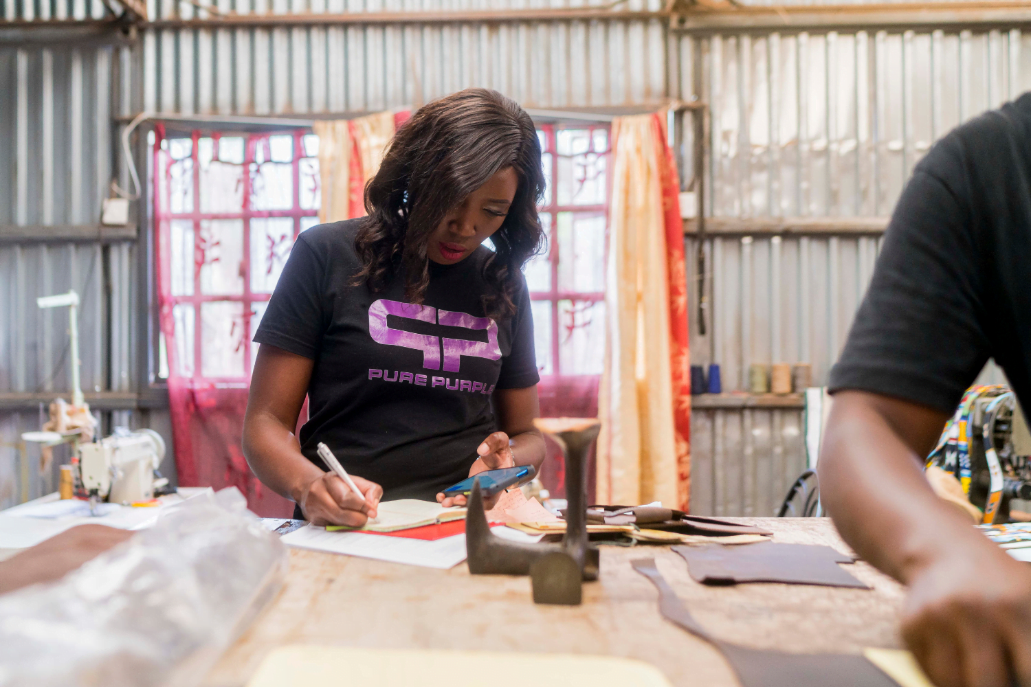 Yolanda Odida sketches something on a piece of paper in her workshop at Pure Purple.