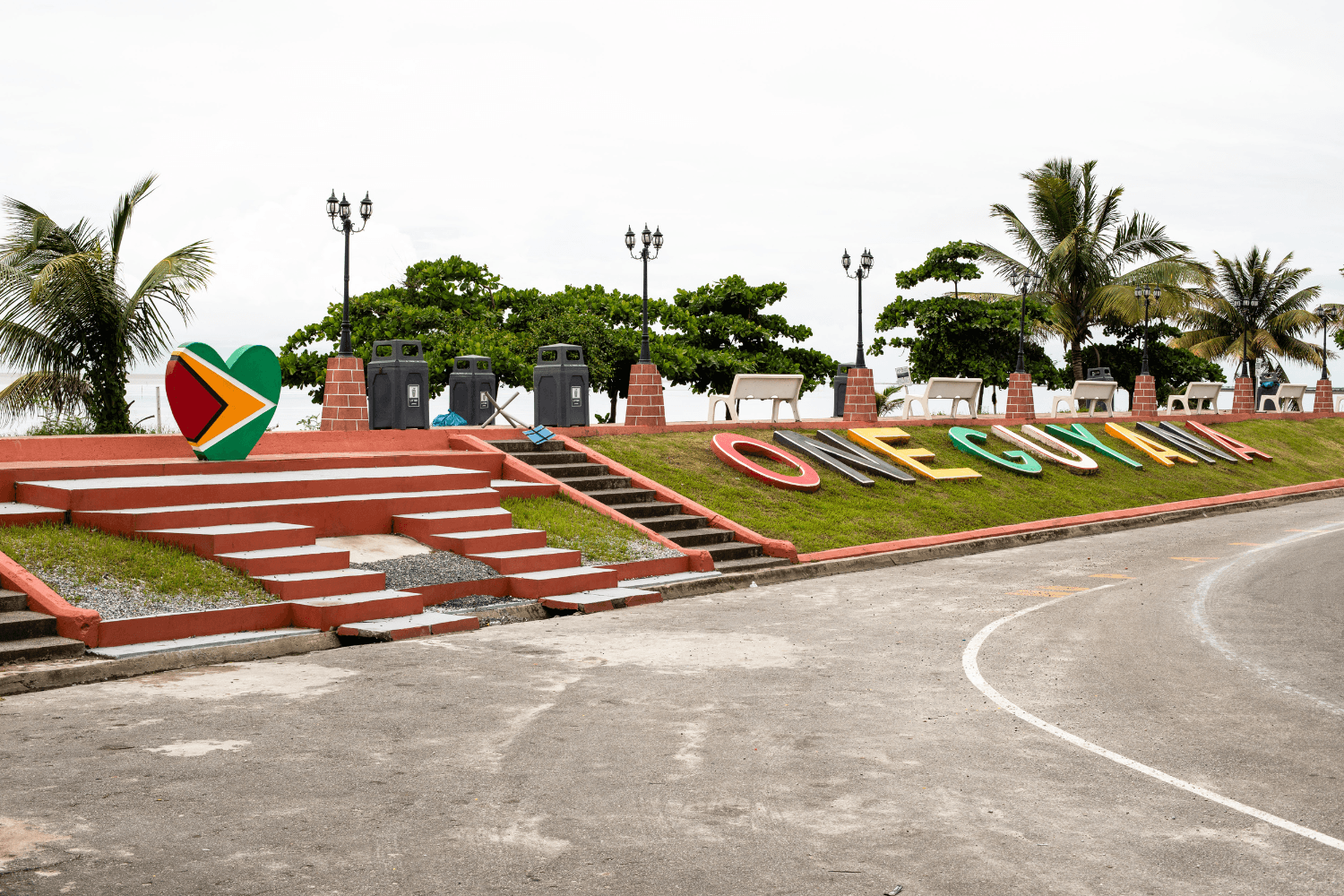 Large colourful letters spell 'One Guyana' on the roadside.
