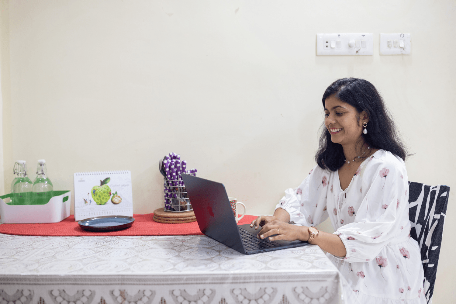 Prachi Robinson, a woman entrepreneur from India is typing on her laptop and smiling.