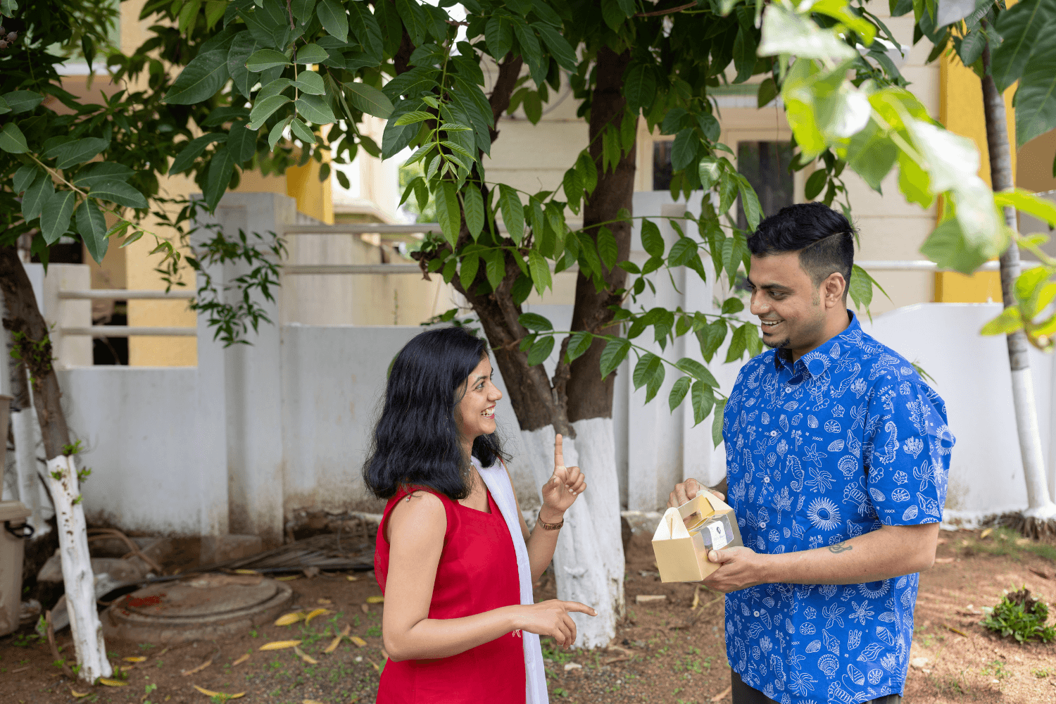 Prachi Robinson, a woman entrepreneur from India is smiling and talking to a smiling man, who holds a takeaway box of cookies in his hands.