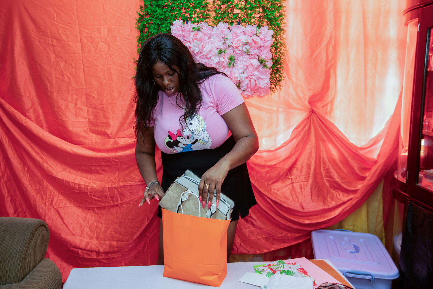 Guyanese entrepreneur Latifah Browne puts a handbag into an orange purchasing bag.