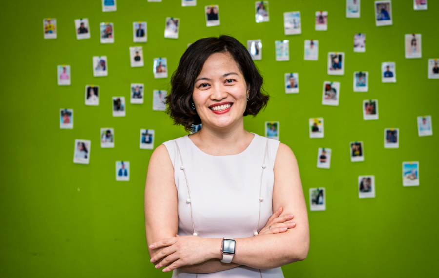 Van Dang CEO at Savvycom and former mentee and mentor smiles in front of a photo wall.