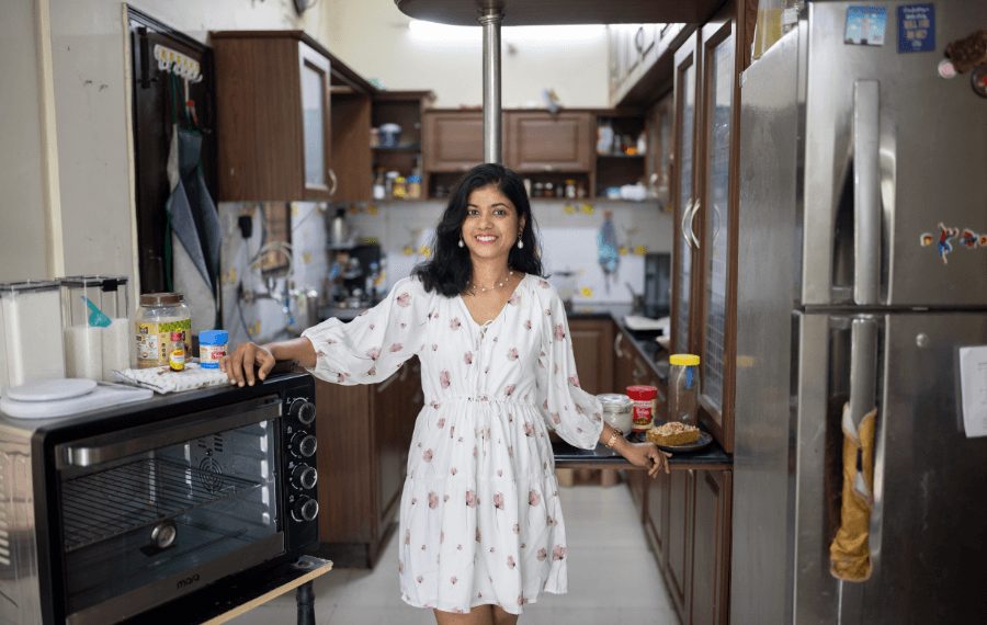 Prachi Robinson, a woman entrepreneur from India stands in the middle of a kitchen. She is smiling at the camera, with one hand resting on an oven and the other on a countertop.